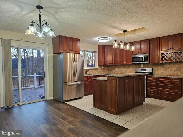 a kitchen with stainless steel appliances granite countertop a refrigerator oven a sink dishwasher and wooden cabinets with wooden floor