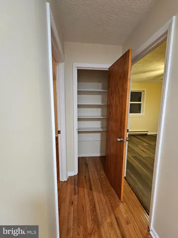 a walk in closet with wooden floor
