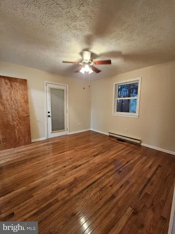 a view of a room with wooden floor and a ceiling fan