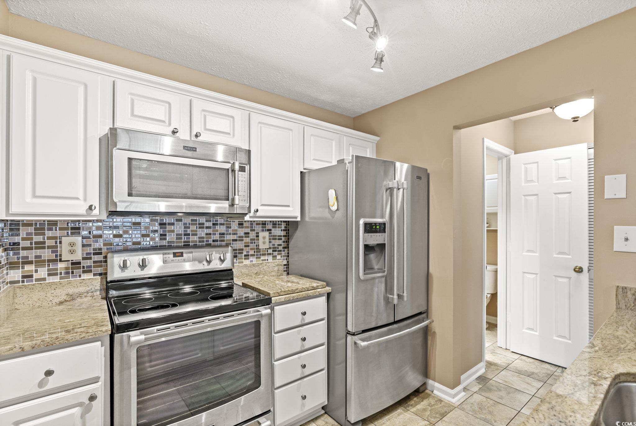 613 14th Avenue South, Unit 34 Surfside Beach, SC 29575 - Photo 11 of 37 Kitchen featuring stainless steel appliances, a textured ceiling, white cabinetry, backsplash, and rail lighting