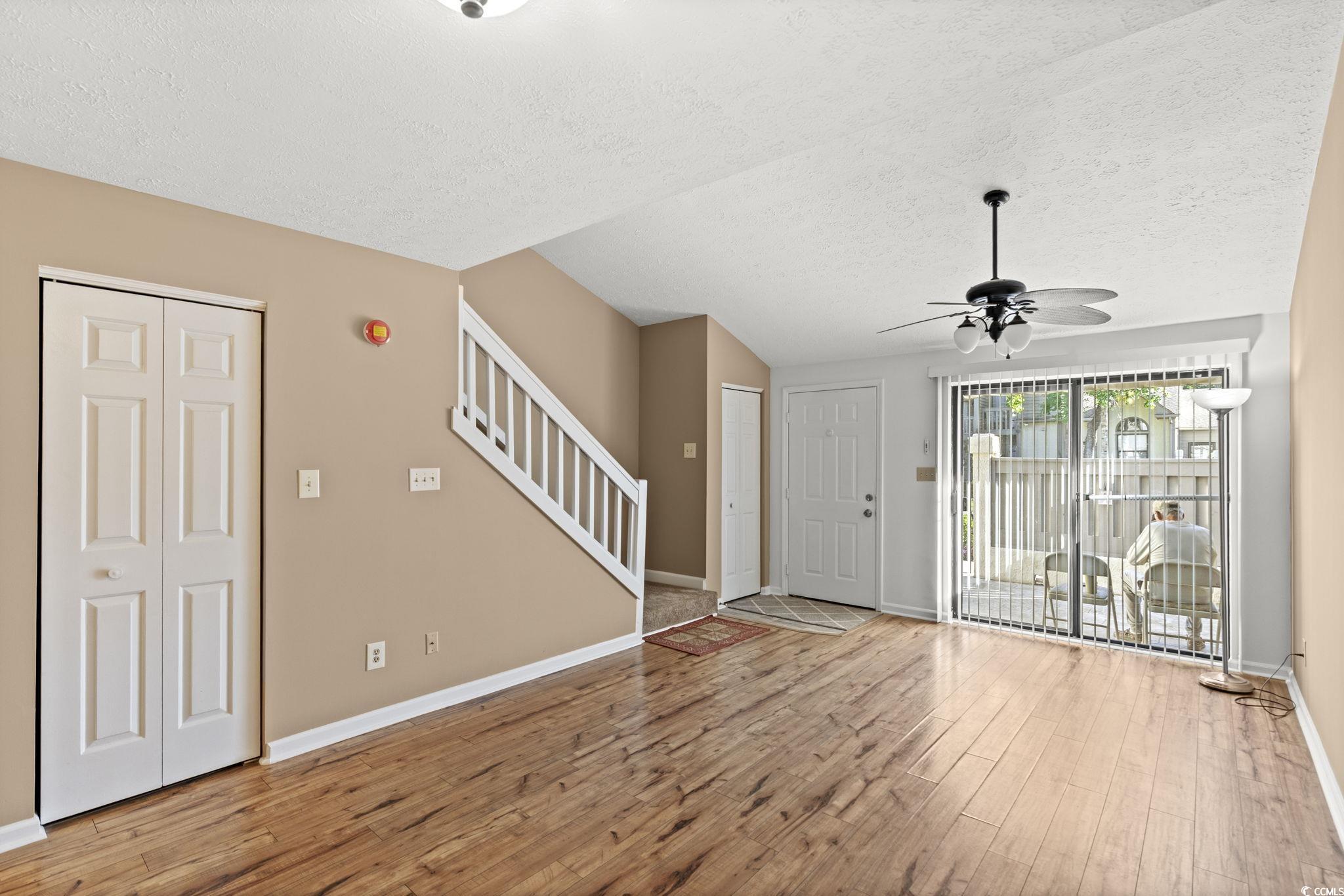 613 14th Avenue South, Unit 34 Surfside Beach, SC 29575 - Photo 7 of 37 Unfurnished living room with light wood-type flooring, a textured ceiling, stairs, and ceiling fan
