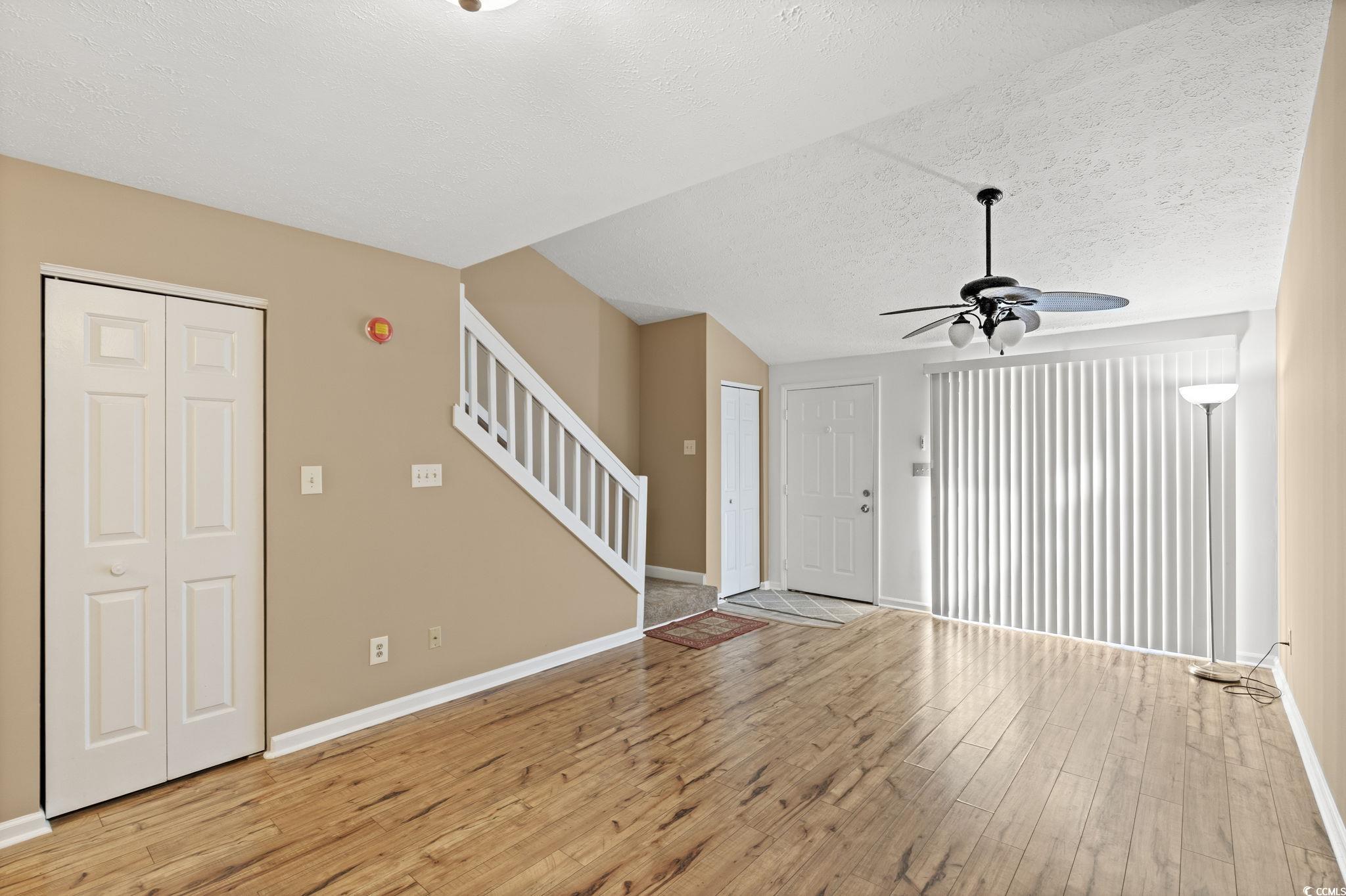 613 14th Avenue South, Unit 34 Surfside Beach, SC 29575 - Photo 9 of 37 Unfurnished living room featuring light wood-style flooring, ceiling fan, a textured ceiling, and stairs