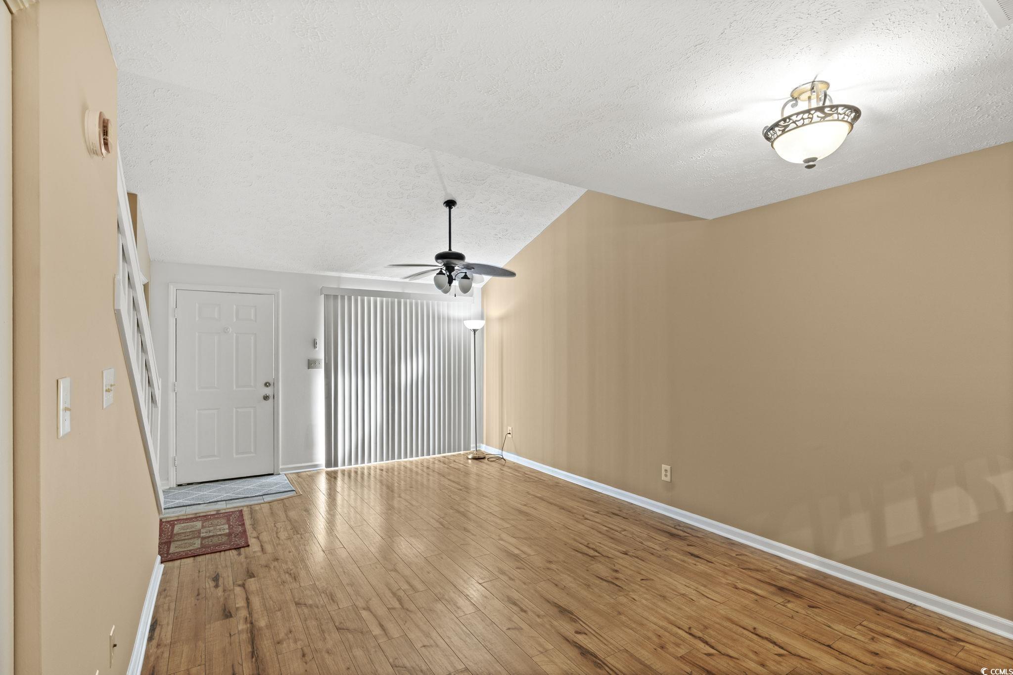 613 14th Avenue South, Unit 34 Surfside Beach, SC 29575 - Photo 10 of 37 Unfurnished living room featuring a textured ceiling, wood finished floors, lofted ceiling, and ceiling fan