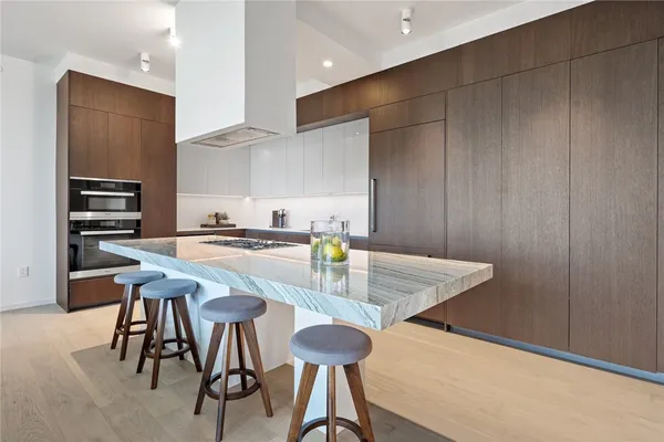 a kitchen with stainless steel appliances kitchen island granite countertop a table chairs and a refrigerator