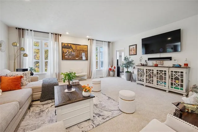 a living room with lots of white furniture and a large window