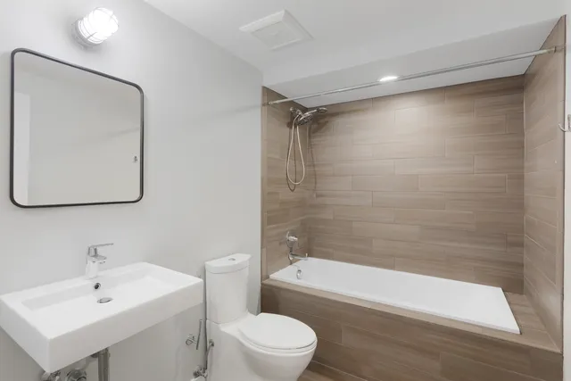 a bathroom with a bathtub shower sink vanity mirror and toilet
