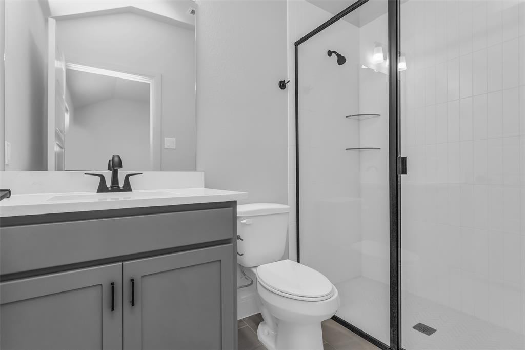 1031 Rylan Street Midlothian, TX 76065 - Photo 16 of 28 Bathroom featuring a grey vanity with a white countertop, matte black fixtures, a frameless mirror, and a glass-enclosed shower with white subway tile