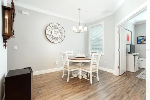 a dining room with wooden floor a chandelier a wooden table and chairs