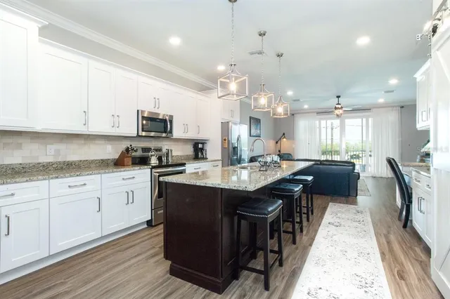 a kitchen with granite countertop a sink a counter space appliances and cabinets