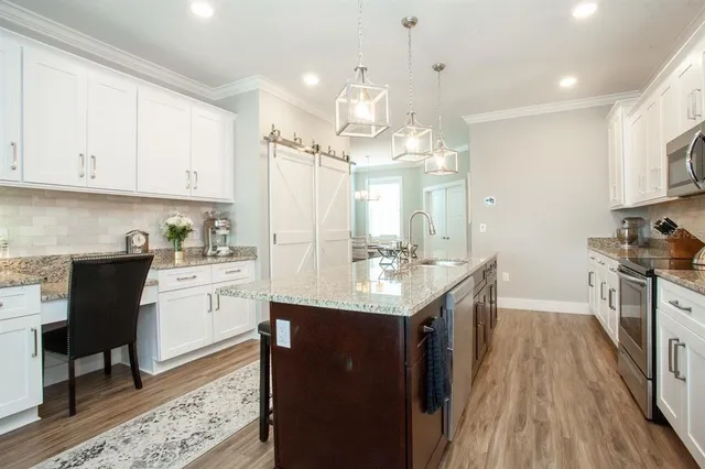 a kitchen with kitchen island granite countertop a sink appliances cabinets and furniture