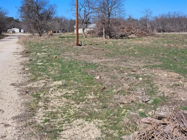 a view of dirt field with trees in the background