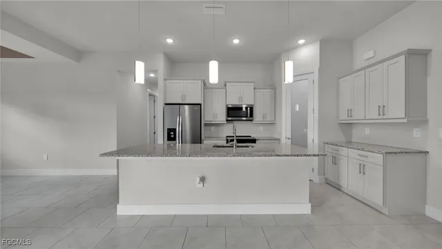 a large kitchen with stainless steel appliances a refrigerator a sink dishwasher a oven and white cabinets with wooden floor