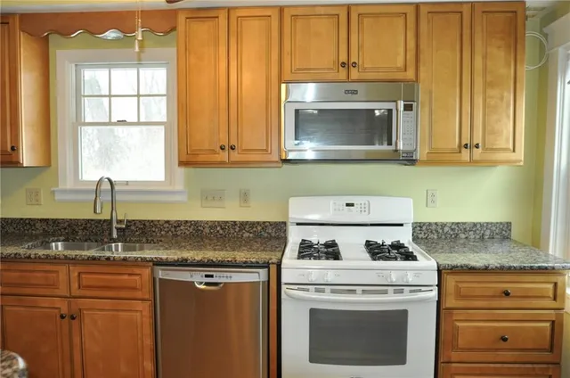 a kitchen with granite countertop cabinets stainless steel appliances and a sink