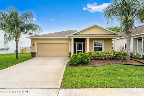 a front view of a house with a garden and palm trees
