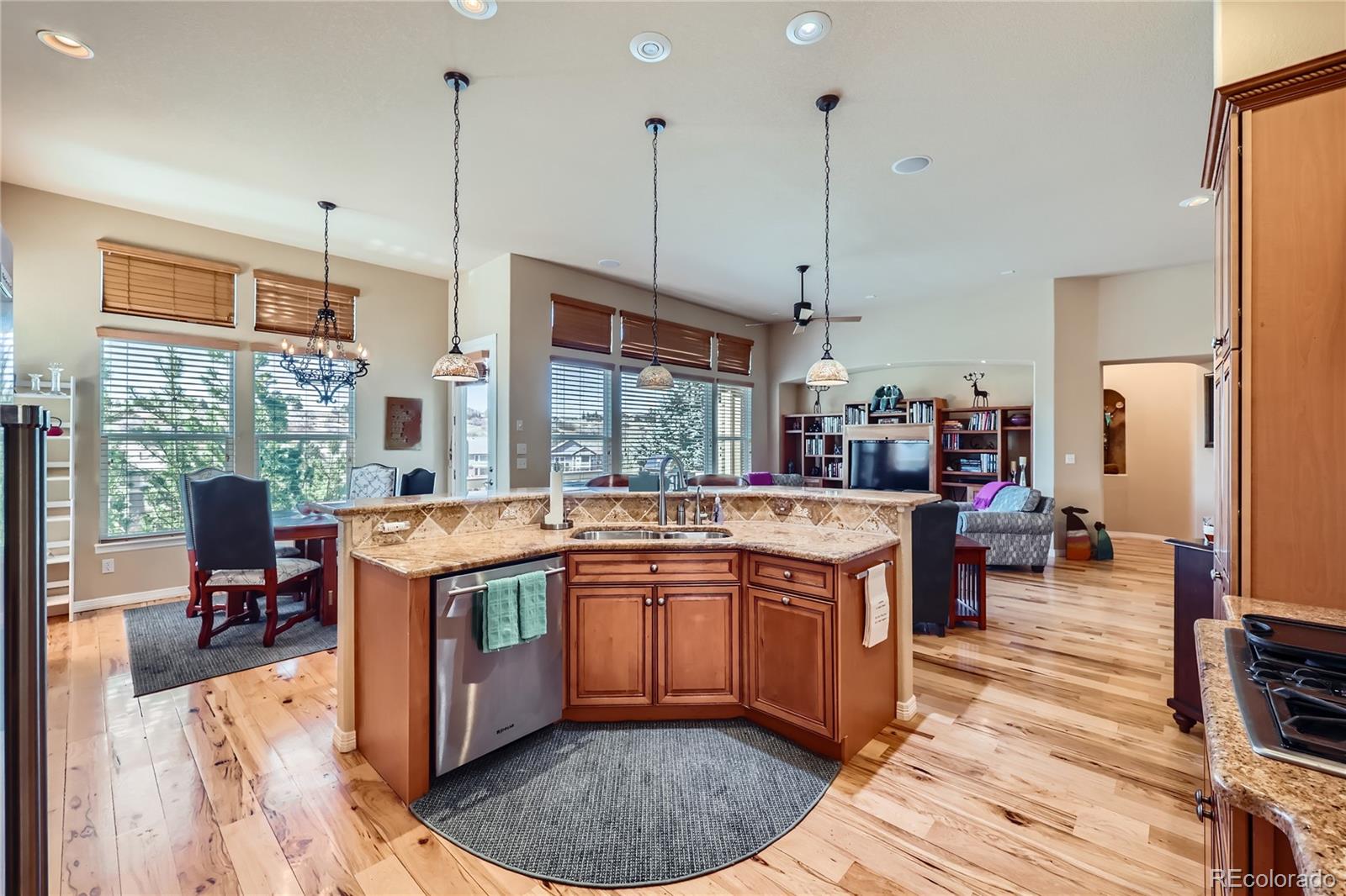 7009 Winter Ridge Place Castle Pines, CO 80108 - Photo 7 of 42 a kitchen with stainless steel appliances granite countertop a sink a stove and a wooden floors