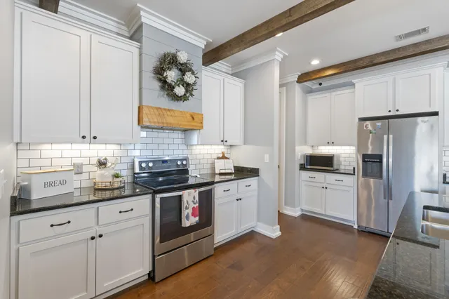 a very nice looking kitchen with granite countertop a stove oven and a dining table with wooden floor