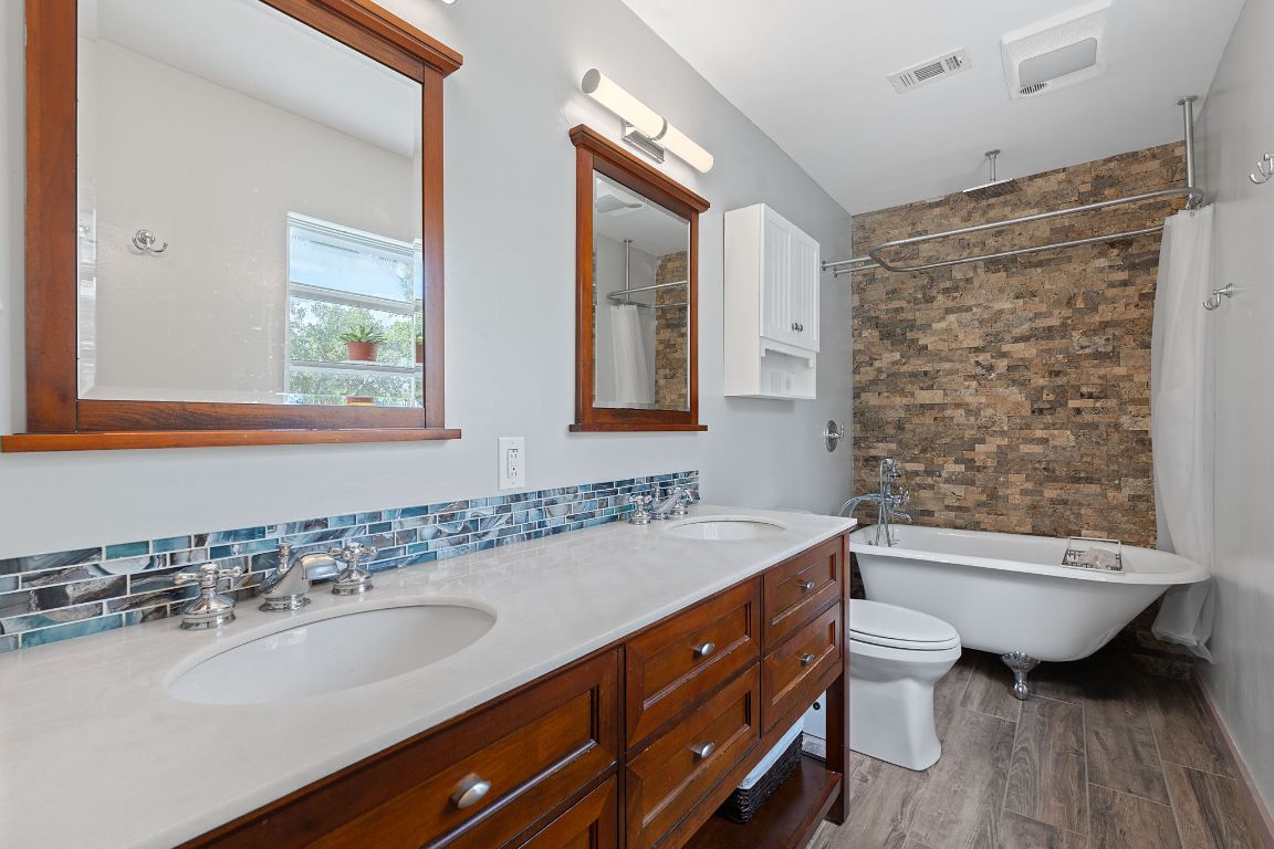 8705 South View Road Austin, TX 78737 - Photo 17 of 39 a bathroom with a double vanity sink a mirror and a bathtub
