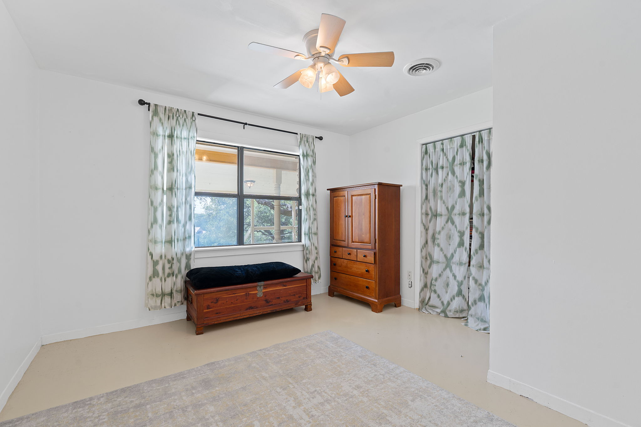 8705 South View Road Austin, TX 78737 - Photo 20 of 39 Bright bedroom with Ceiling Fan and Large window overlooking Front Yard. Concrete Flooring.