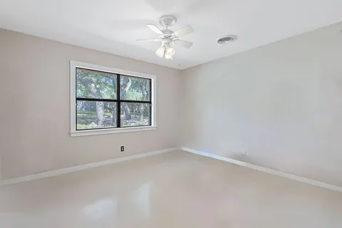 an empty room with windows and chandelier fan