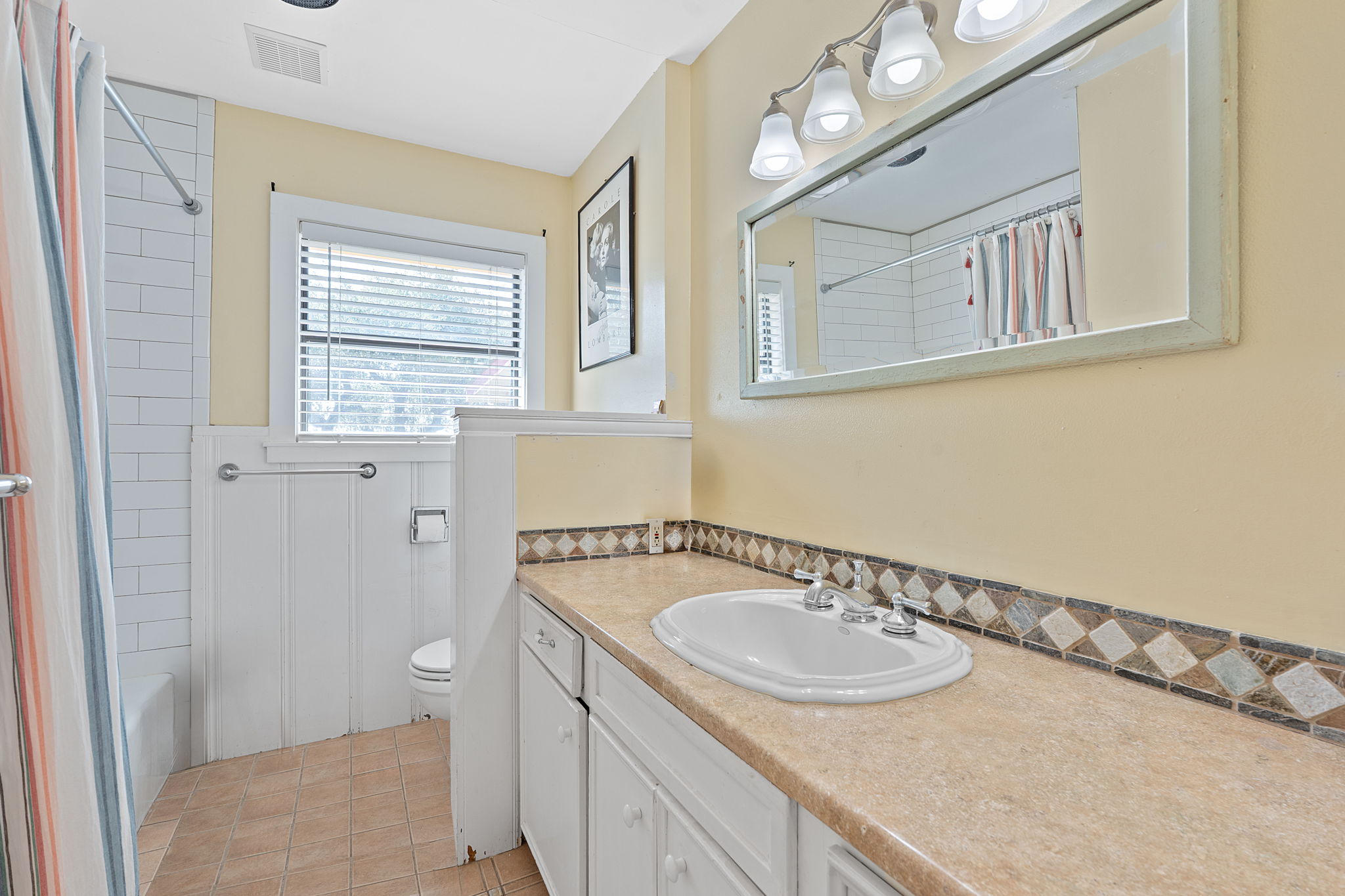 8705 South View Road Austin, TX 78737 - Photo 23 of 39 Updated Hall Bathroom with White Subway tile shower, decorative tile border, beige countertop, and ample Natural Light.