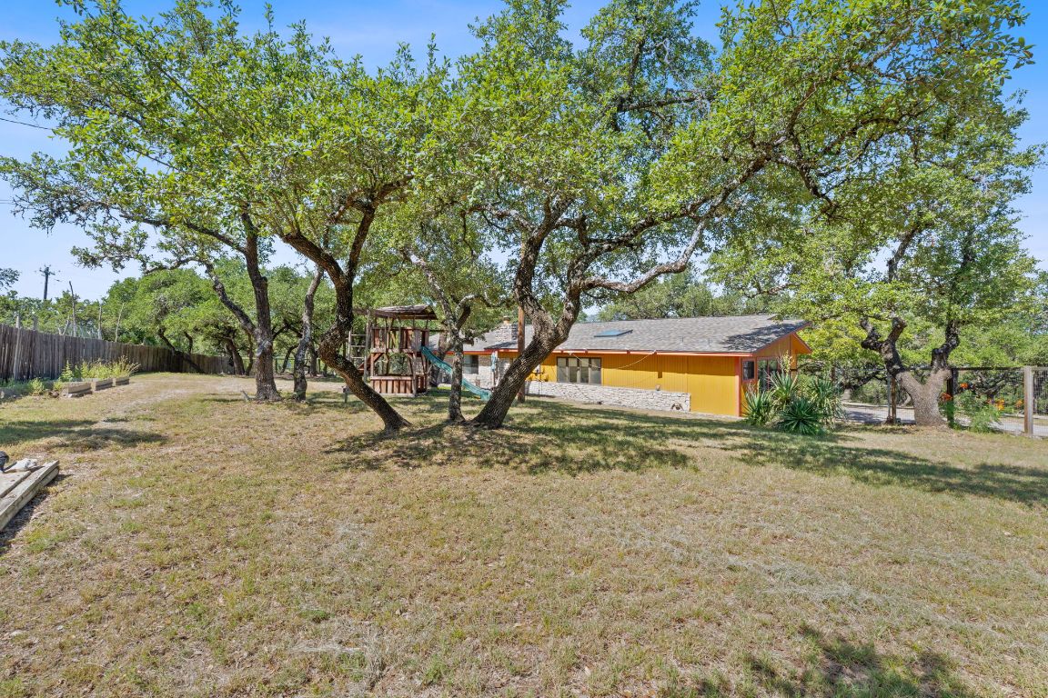 8705 South View Road Austin, TX 78737 - Photo 29 of 39 a backyard of a house with large trees and a wooden fence