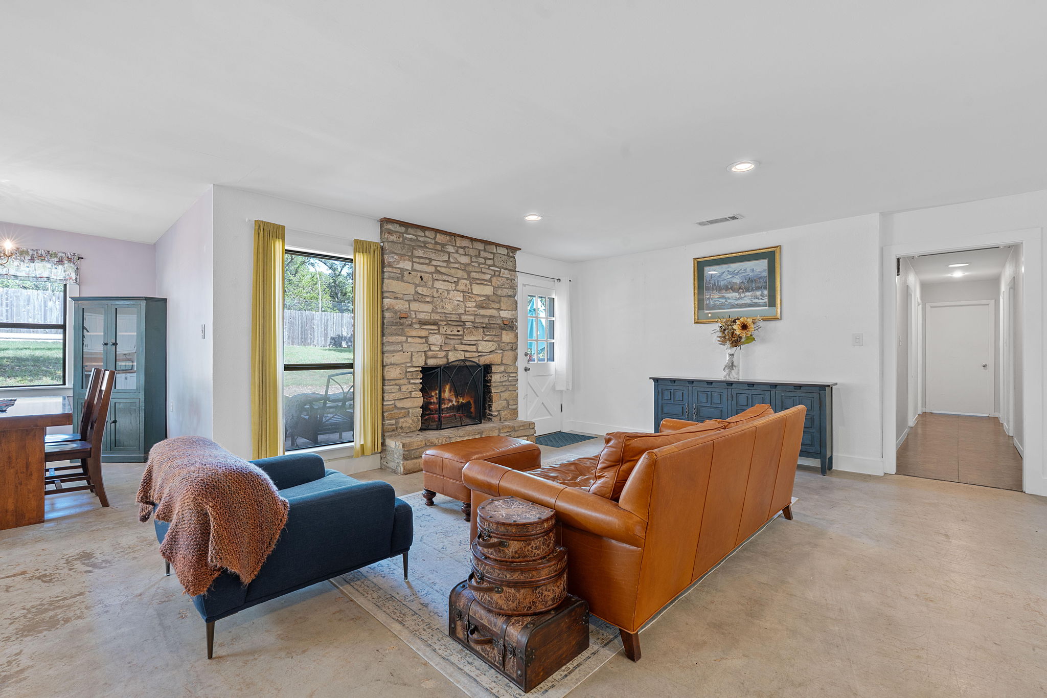 8705 South View Road Austin, TX 78737 - Photo 6 of 39 Bright, Open Concept Living Area Featuring Stunning Stone Fireplace and Large Windows. Polished concrete floors, recessed lighting, and natural light create an inviting atmosphere. Access to backyard.
