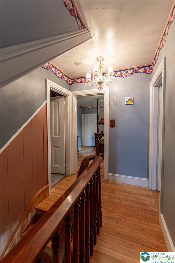 2485 Hieter Road Quakertown, PA 18951 - Photo 25 of 97 A classic chandelier illuminates the hallway, highlighting the beautiful wood flooring and traditional staircase railing.