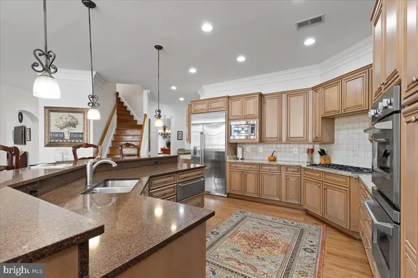 a kitchen with stainless steel appliances kitchen island granite countertop a stove a refrigerator a sink and a dining table with wooden floor