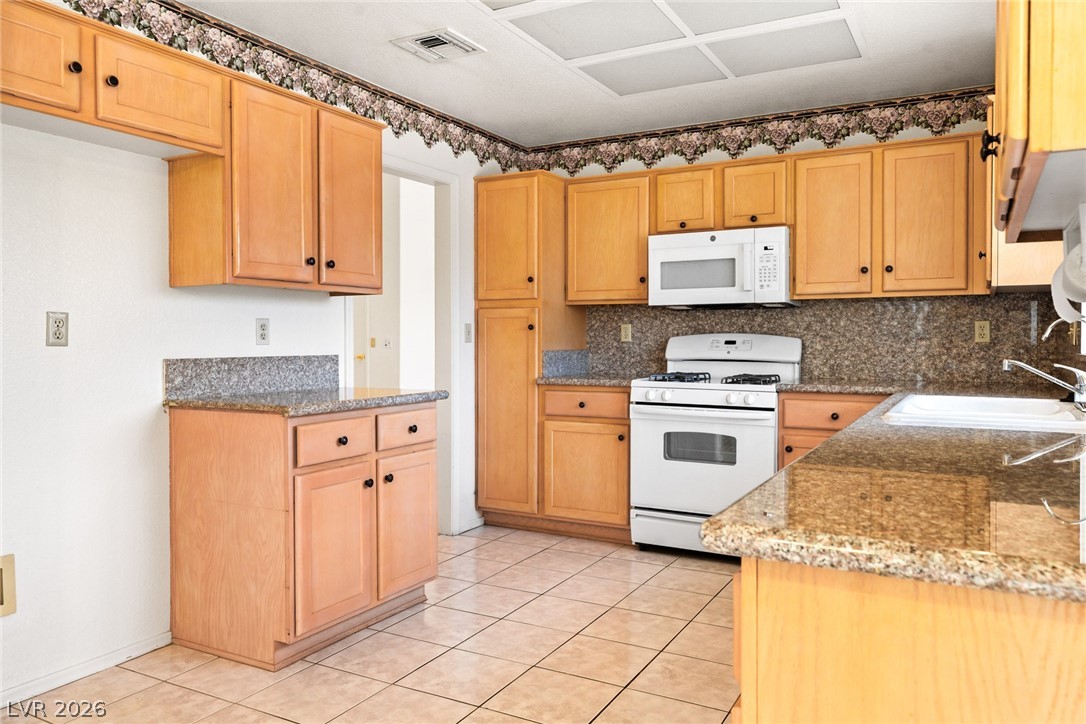 9433 Quail Ridge Drive Las Vegas, NV 89134 - Photo 16 of 25 This functional kitchen features ample cabinetry, granite counters, and modern appliances.