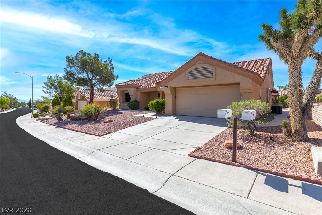 9433 Quail Ridge Drive Las Vegas, NV 89134 - Photo 2 of 25 This desert oasis features a neatly paved driveway and well-maintained landscaping under a clear sky.