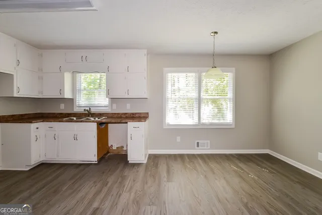 a kitchen with granite countertop wooden floors white cabinets and window