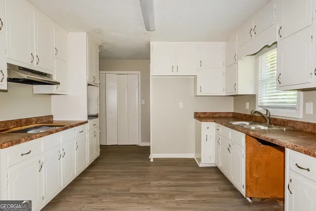 a kitchen with granite countertop a sink stove and cabinets