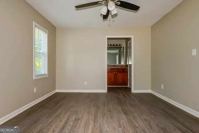 an empty room with wooden floor cabinet and windows