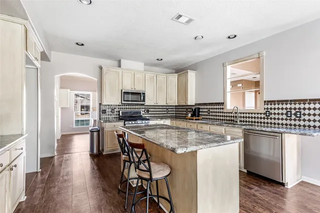 a kitchen with stainless steel appliances granite countertop a sink a stove and a wooden floors