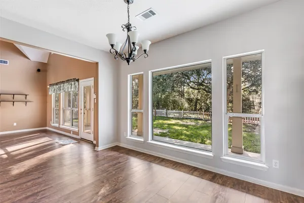 a view of a livingroom with a chandelier windows and wooden floor