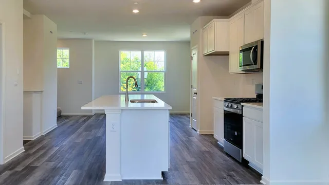 a kitchen with stainless steel appliances a kitchen island hardwood floor sink stove and wooden cabinets