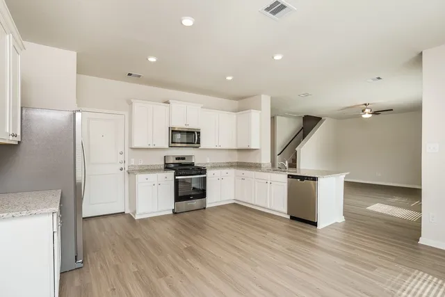 a kitchen with stainless steel appliances a refrigerator and wooden floor