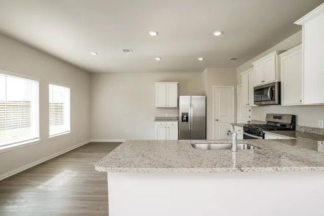 a kitchen with stainless steel appliances granite countertop a sink a stove a microwave and a refrigerator