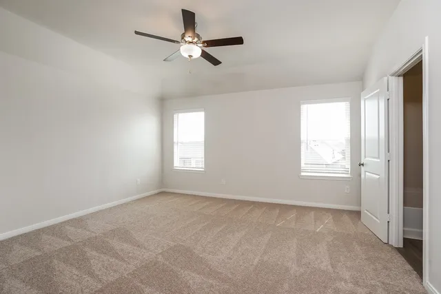 an empty room with windows and fan