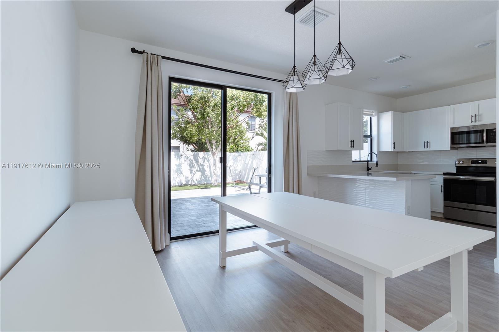 3435 West 105th Street Hialeah, FL 33018 - Photo 7 of 41 a large kitchen with sink a refrigerator and wooden floor