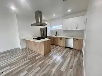 a kitchen with a stove wooden floor and a refrigerator