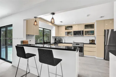 a kitchen with stainless steel appliances a sink a stove a refrigerator cabinets and a dining table with wooden floor