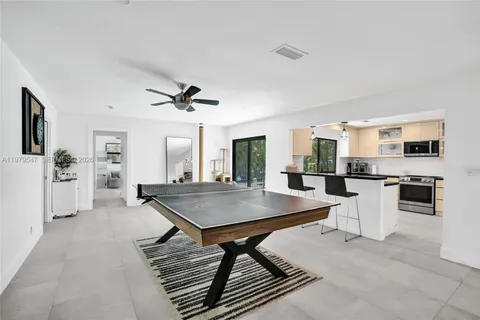 a kitchen with stainless steel appliances kitchen island granite countertop a stove a sink dishwasher and white cabinets with wooden floor