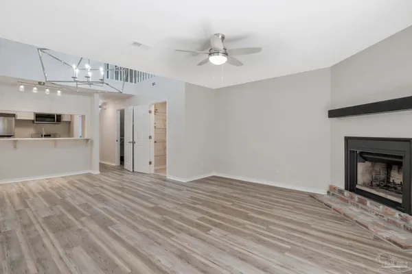 a view of an empty room with wooden floor and a kitchen