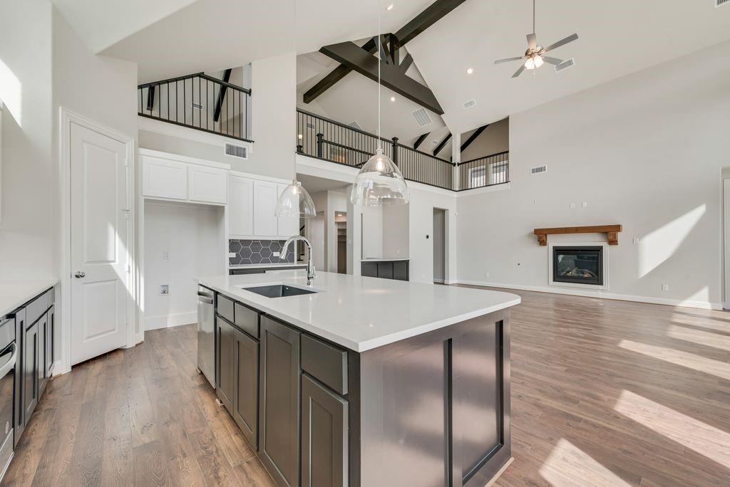 1231 Calebria Way Fate, TX 75087 - Photo 14 of 40 a kitchen that has a microwave a stove and white cabinets with wooden floor