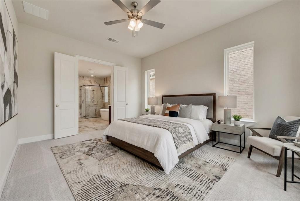 1231 Calebria Way Fate, TX 75087 - Photo 20 of 40 a bedroom with a large bed and a chandelier