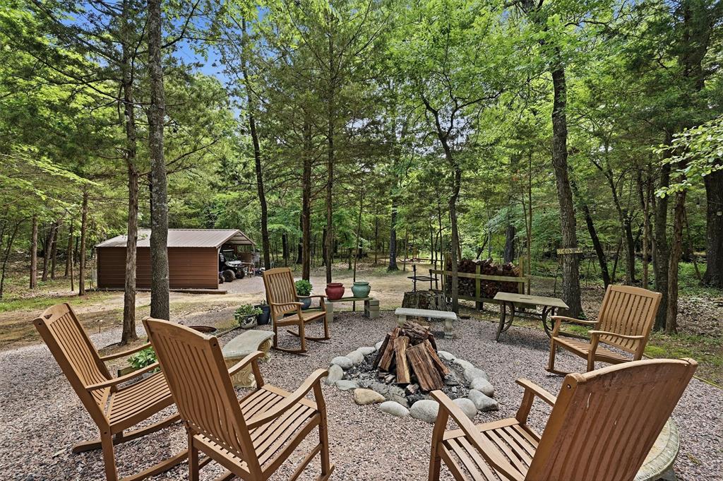 3958 Ranch Road Whitesboro, TX 76273 - Photo 31 of 40 Outdoor fire pit area with stone surround, surrounded by mature trees