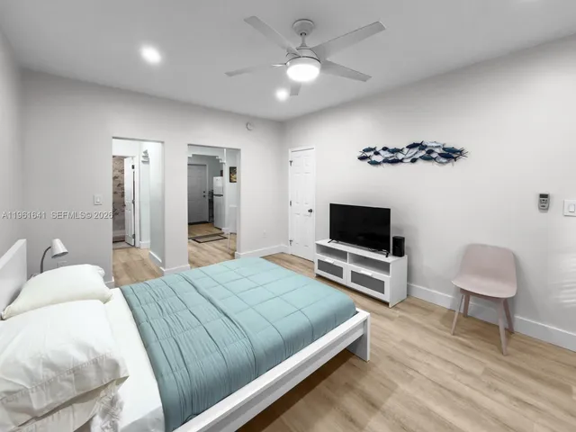 a bedroom with a bed tv and a chair