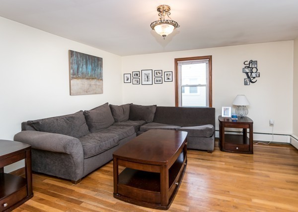 1131 Trapelo Road Waltham, MA 02451 - Photo 12 of 23 a living room with furniture a dining table and paintings on the wall with wooden floor