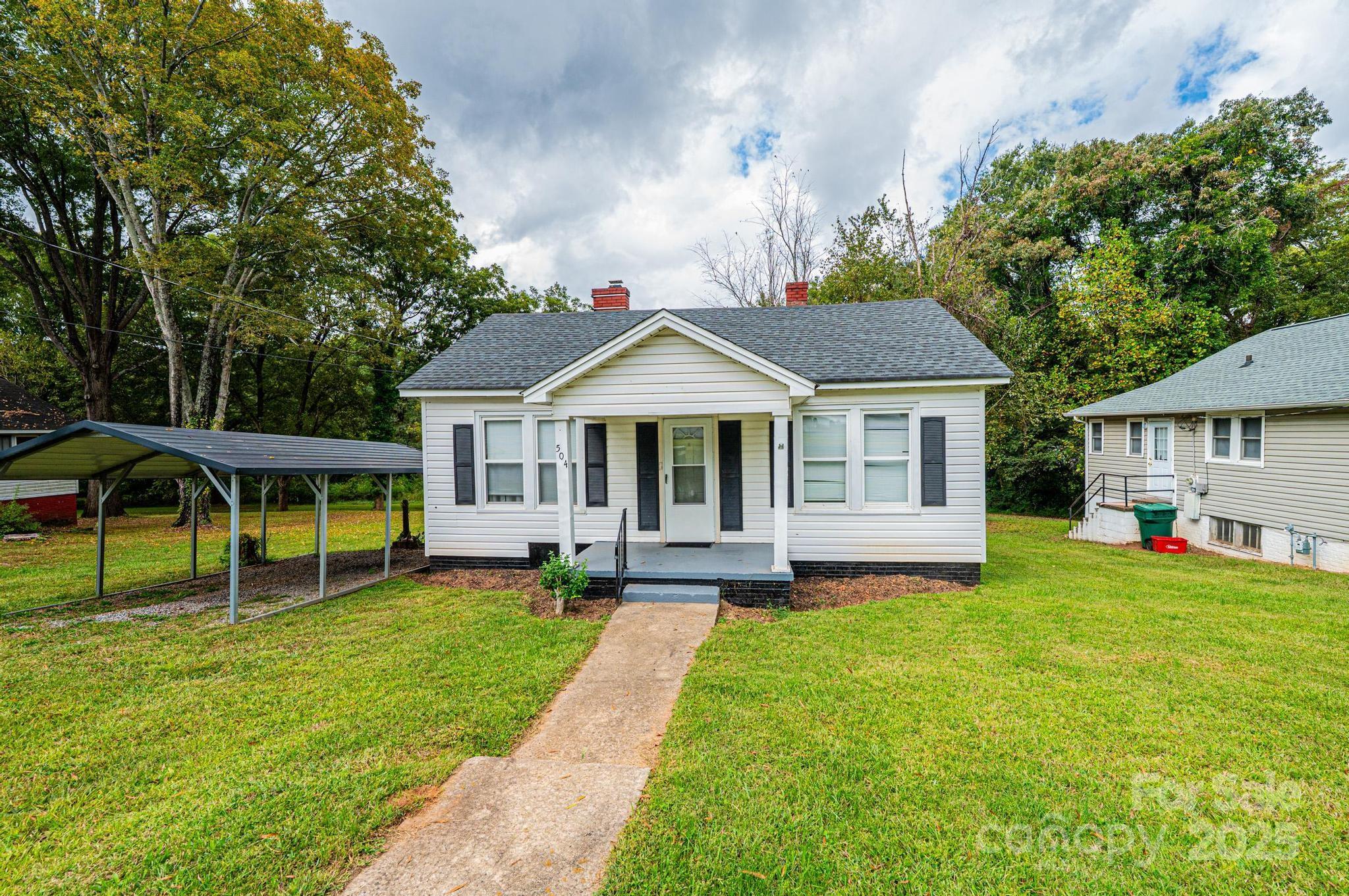 504 North Spring Avenue Newton, NC 28658 - Photo 3 of 35 a front view of a house with a garden and trees